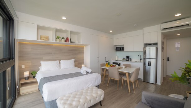 Une chambre d’hôtel moderne dotée d’un grand lit, d’un coin repas et d’une kitchenette.