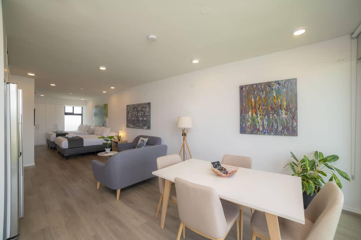 Una sala de estar moderna con una mesa de comedor, sofás y un cuadro abstracto grande.