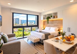 Une chambre d’hôtel moderne dotée d’une grande fenêtre, d’un lit, d’un coin repas et d’un espace salon.
