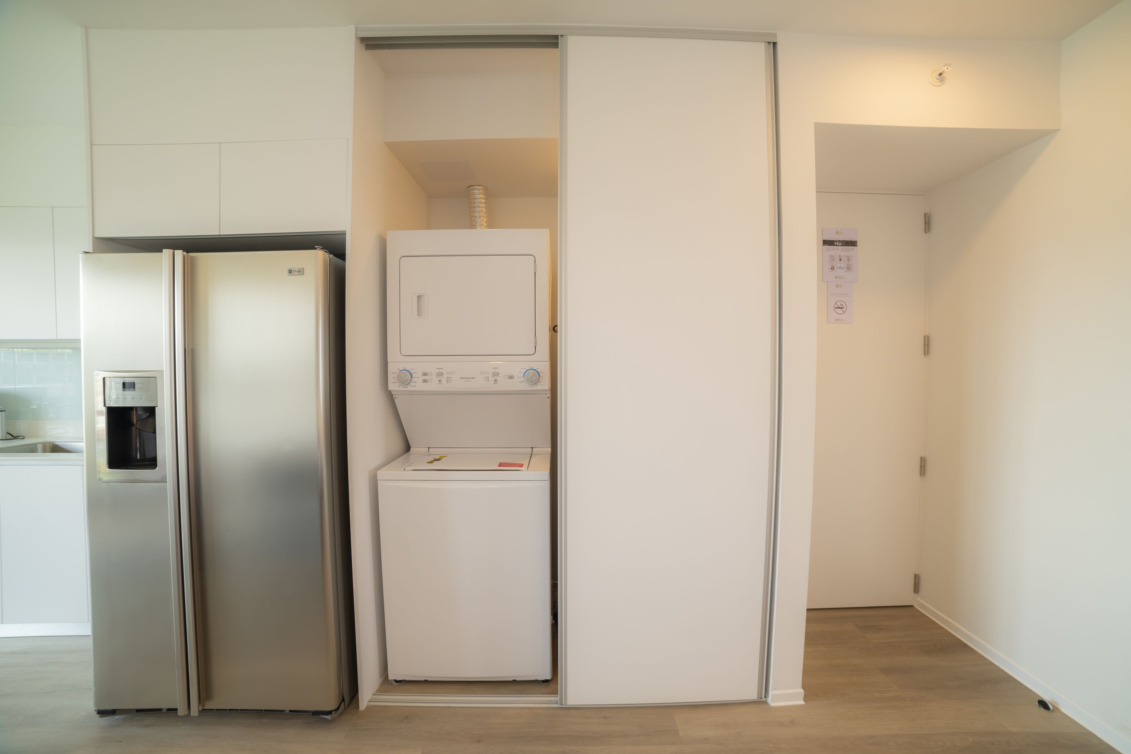 A compact kitchen with a built-in refrigerator, a washing machine, and a water dispenser.