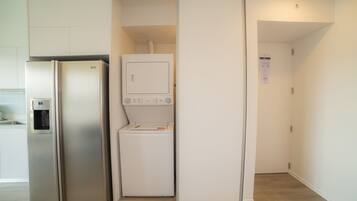 A compact kitchen with a built-in refrigerator, a washing machine, and a water dispenser.