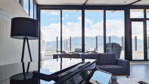 Un salon moderne avec une grande fenêtre, un piano, un canapé et une table basse.