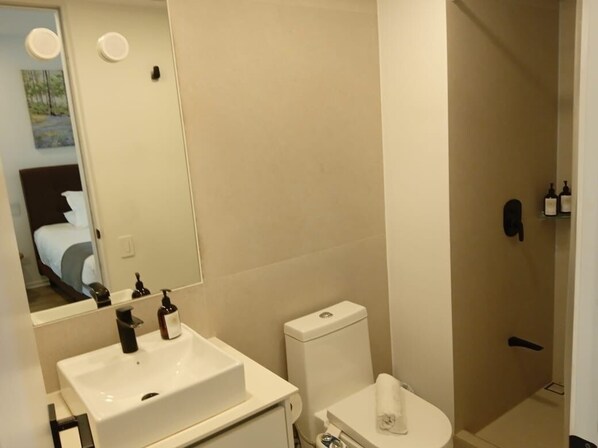 Un baño con lavamanos, inodoro y ducha blancos.
