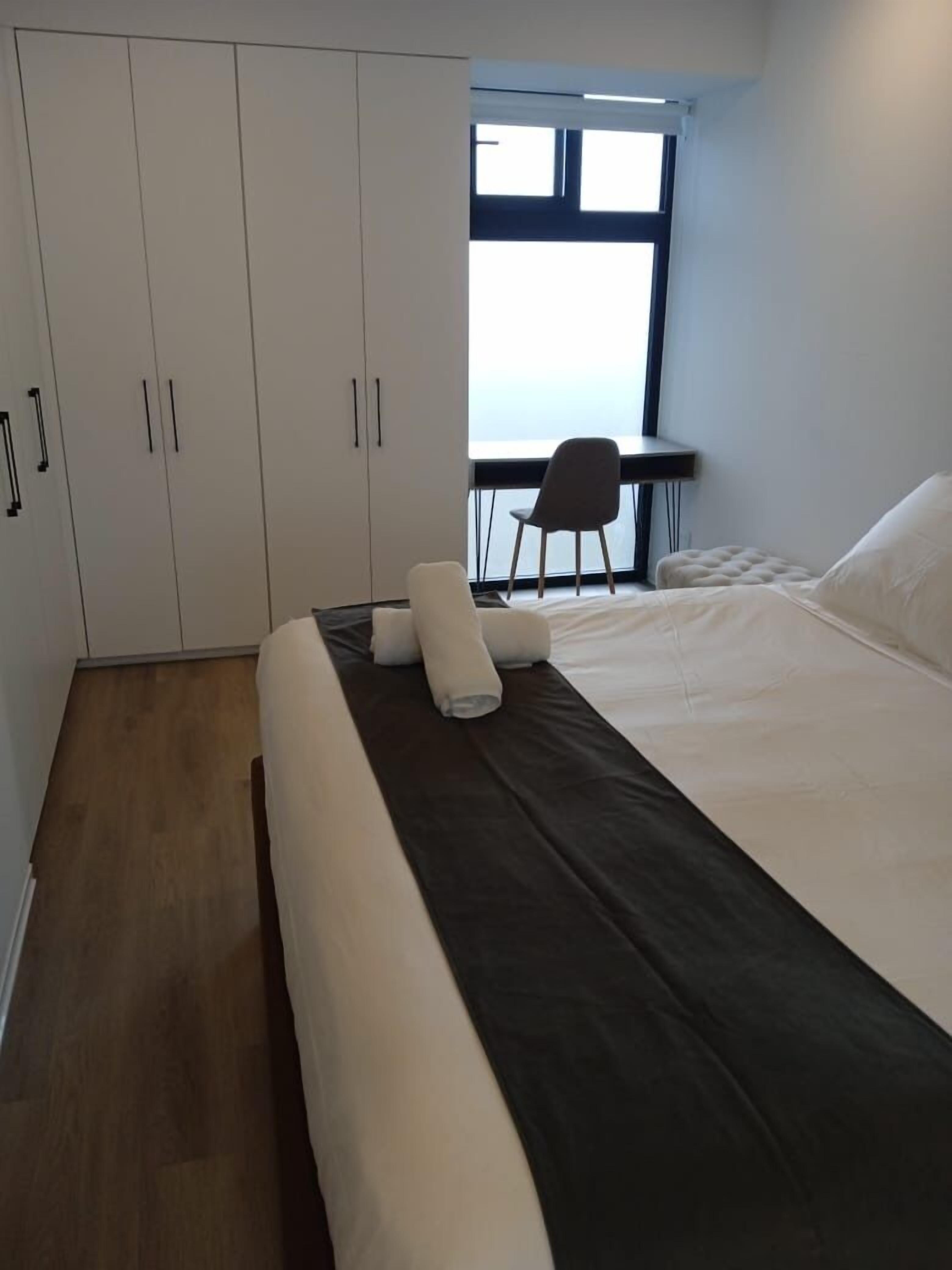 Un dormitorio moderno con una cama grande, un escritorio y una silla.