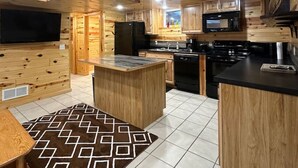 L’intérieur d’une cabane en bois comprend un coin cuisine équipé d’un réfrigérateur, d’un four à micro-ondes, d’une cuisinière et de placards.