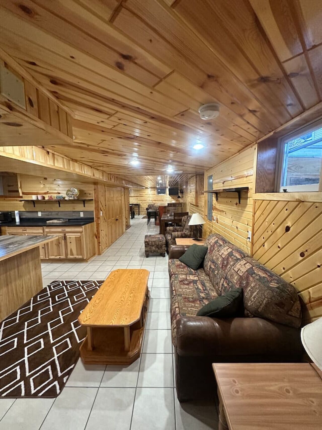 Un interior de madera con sofá, mesa de centro y zona de cocina.