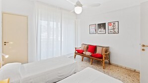 Hotellihuone, jossa on sänky, sohva, kattotuuletin ja ovi.