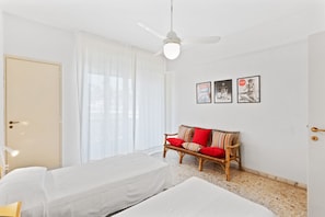 Une chambre d’hôtel avec un lit, un canapé, un ventilateur de plafond et une porte.
