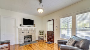 A living room with hardwood flooring, a fireplace, a television, and a leather sofa.