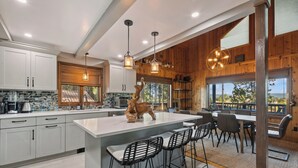 Une cuisine moderne dotée d’un grand îlot central, de tabourets de bar et de luminaires suspendus.