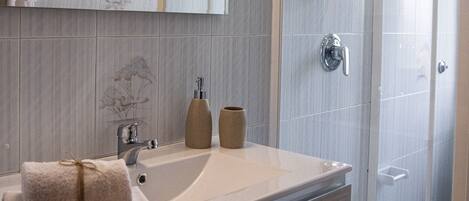 A modern bathroom with a large mirror, a sink with a towel, and a shower area.