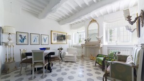 Une pièce dotée d’un sol carrelé en forme d’hexagone, d’une table à manger avec des chaises, d’un canapé, d’un fauteuil, d’un miroir et de tableaux encadrés accrochés au mur.