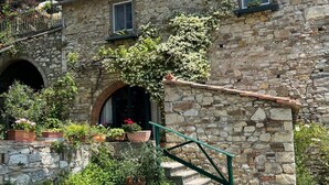 Un bâtiment en pierre doté d’un escalier, de plantes en pot et d’un balcon.