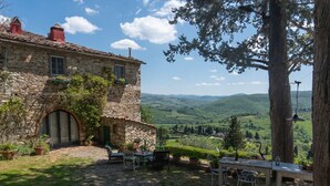Un bâtiment en pierre offrant une vue sur des collines ondoyantes.