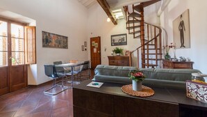 A spacious living area with a dining table, sofa, and a spiral staircase.