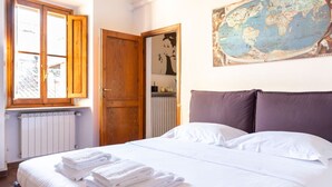 A bedroom with a bed, a window with wooden shutters, a radiator, and a world map on the wall.