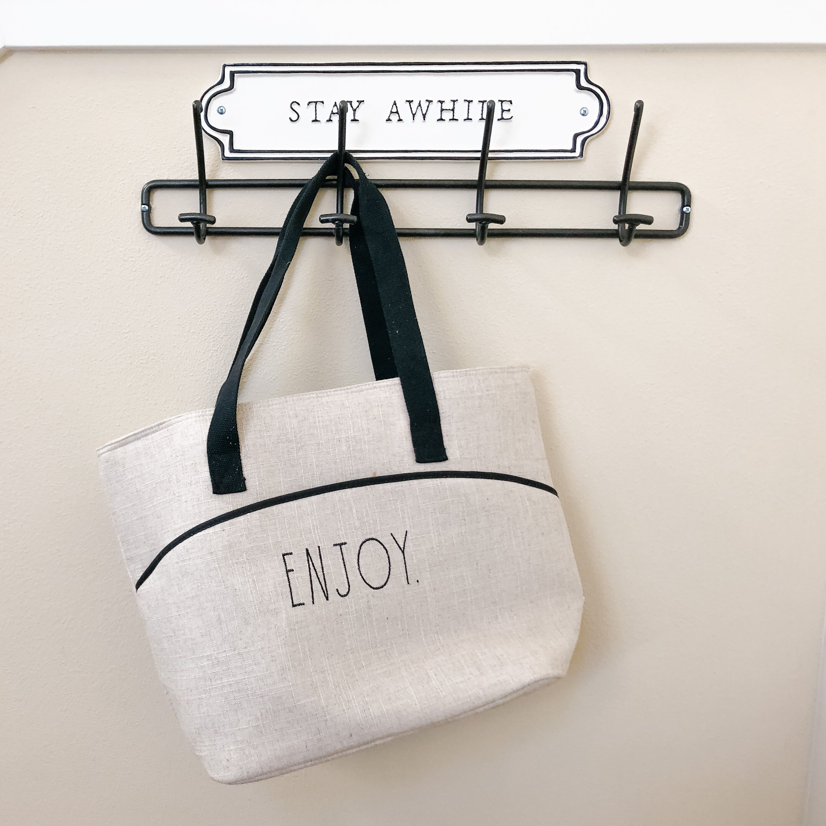 A wall-mounted sign with the words 'STAY AWAY' and a hanging bag with the word 'ENJOY' on it.