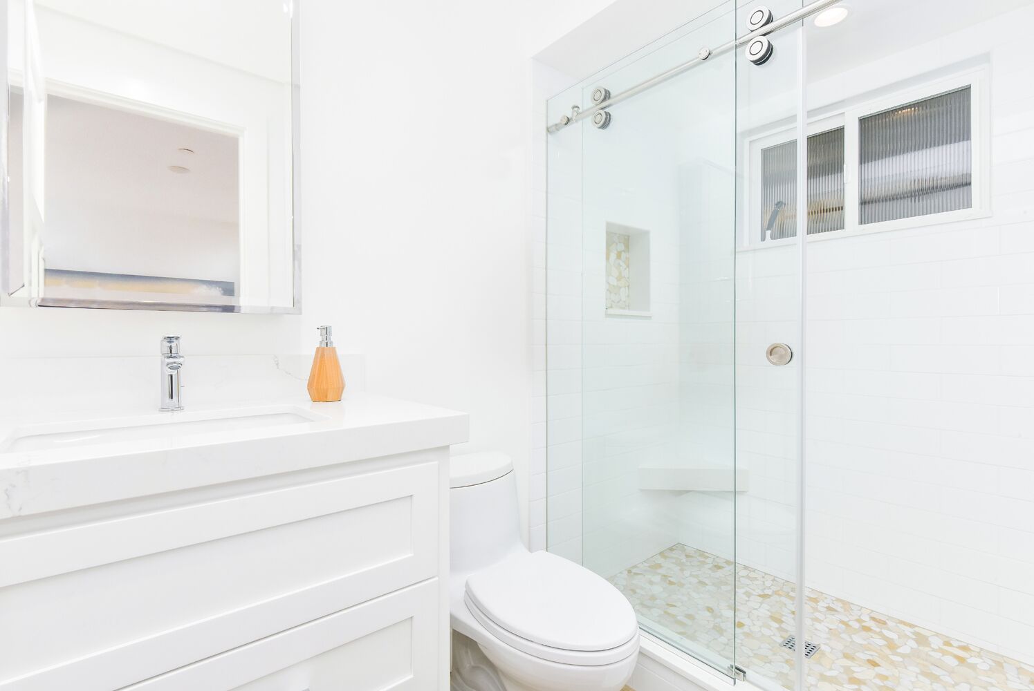 Uma casa de banho moderna com um lavatório branco, cabine de duche em vidro e sanita.