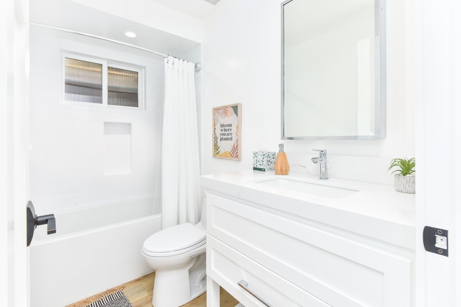 Un baño moderno con bañera, inodoro y un espejo grande.
