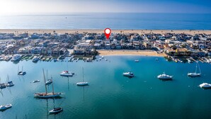 Vista aérea de un pueblo costero con un puerto deportivo lleno de barcos, una playa y edificios residenciales.