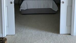 Une chambre à coucher avec un lit, un ventilateur de plafond et une porte donnant sur une autre pièce.