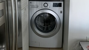 Une petite buanderie équipée d’un lave-linge à chargement par le haut et d’un sèche-linge à chargement frontal.
