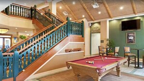 Een zwembadgedeelte met een pooltafel, een trap met blauwe leuningen en een bord voor recreatieve activiteiten.