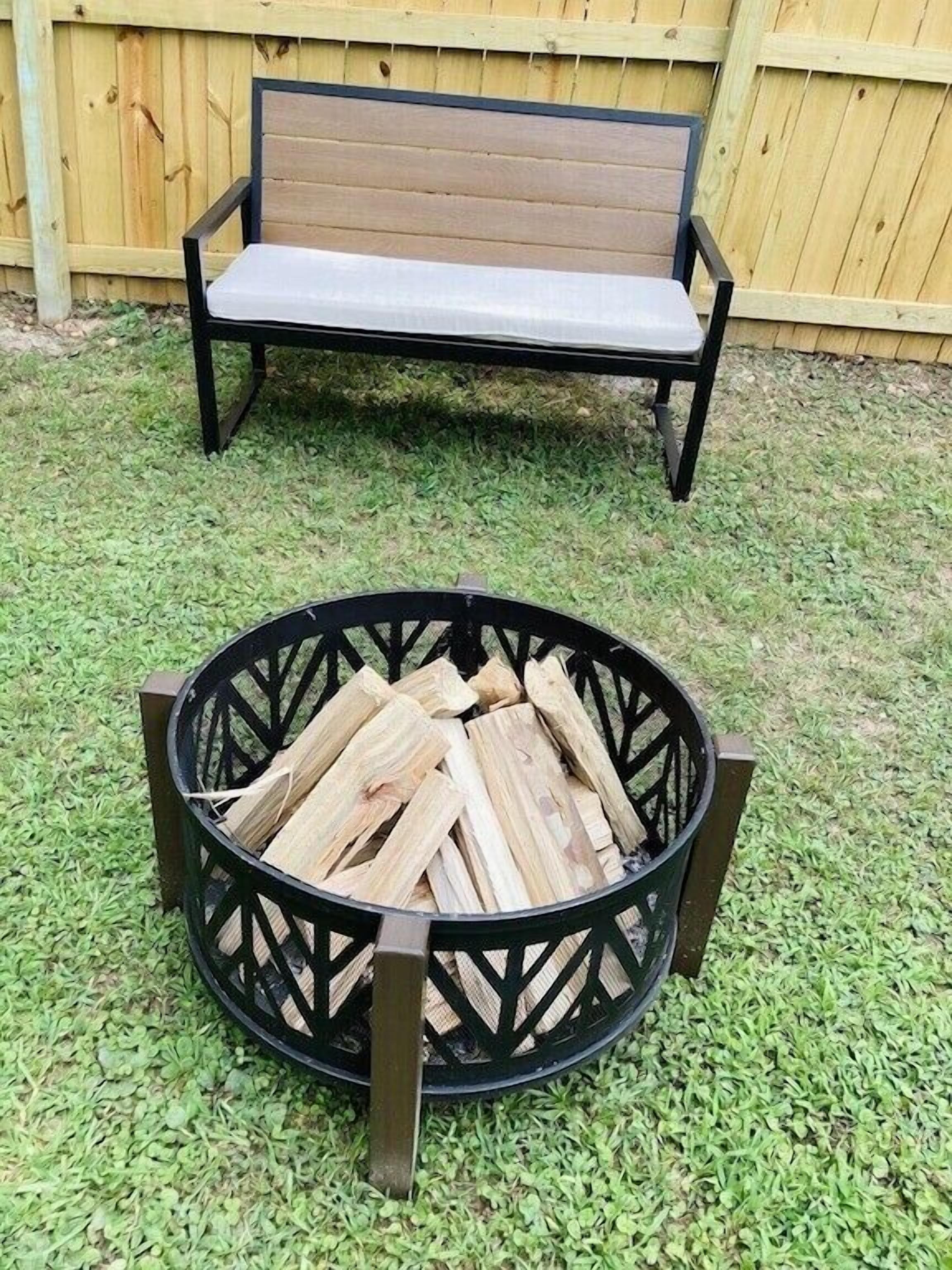 A round fire pit with logs, surrounded by a metal frame, and a bench in the background.