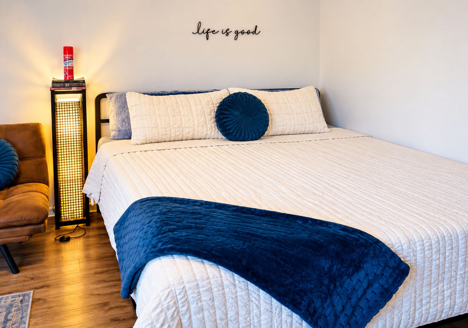 Ein Schlafzimmer mit einem Bett, einem Sessel, einer Stehlampe und einem Wandschild.