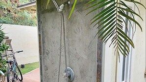 A shower enclosure with a concrete exterior and a metal showerhead.