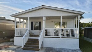 A single-story house with a porch, a staircase leading to the front door, and a number '2156' on the side.