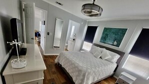 A bedroom with a bed, bedside tables, a dresser, a mirror, and a window.