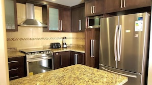 A modern kitchen with dark wood cabinets, stainless steel appliances, and a granite countertop.