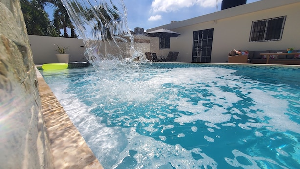 A swimming pool with clear blue water and a stone wall on one side.