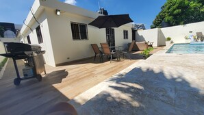 A patio area with a pool, outdoor furniture, and a barbecue grill.