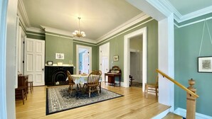 Een eetkamer met houten vloer, een kroonluchter en een open haard.