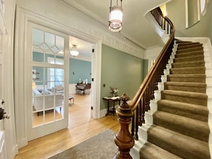 A grand staircase with a wooden handrail and a chandelier above.