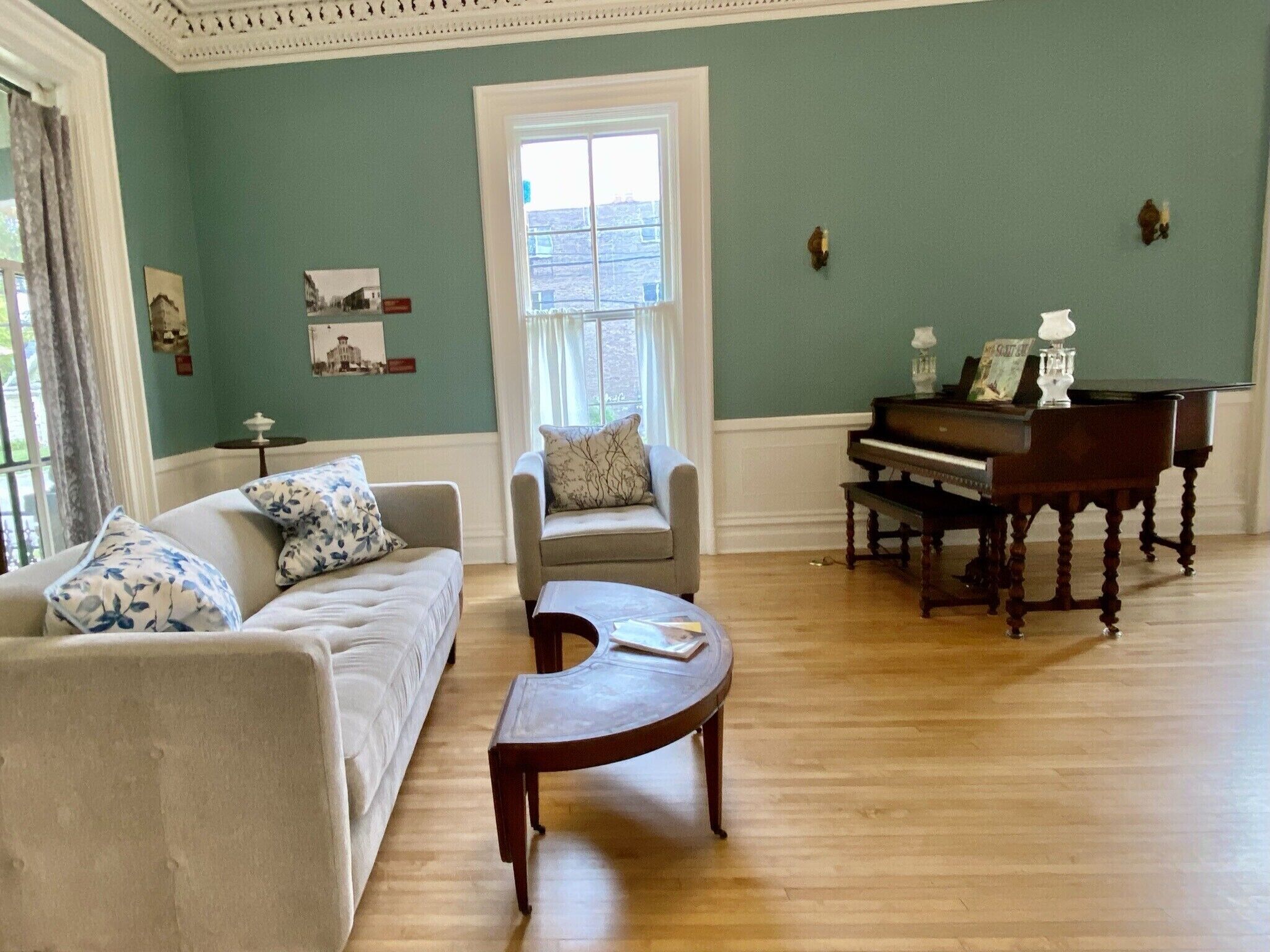 A living room with a piano, two sofas, a coffee table, and a window with curtains.