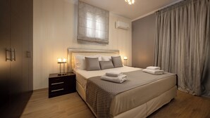 A modern bedroom with a large bed, bedside tables, a wardrobe, and a window with curtains. - Villa Alexandros luxury achillion corfu  (Corfu)