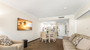 Ein Wohnzimmer mit Essbereich, eine Küche im Hintergrund und ein großes Gemälde an der Wand.