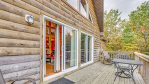 Una cabaña de madera con terraza, puertas corredizas de vidrio y mobiliario exterior.