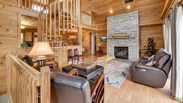 Un interior de madera con chimenea, un sofá, una mesa y una escalera.