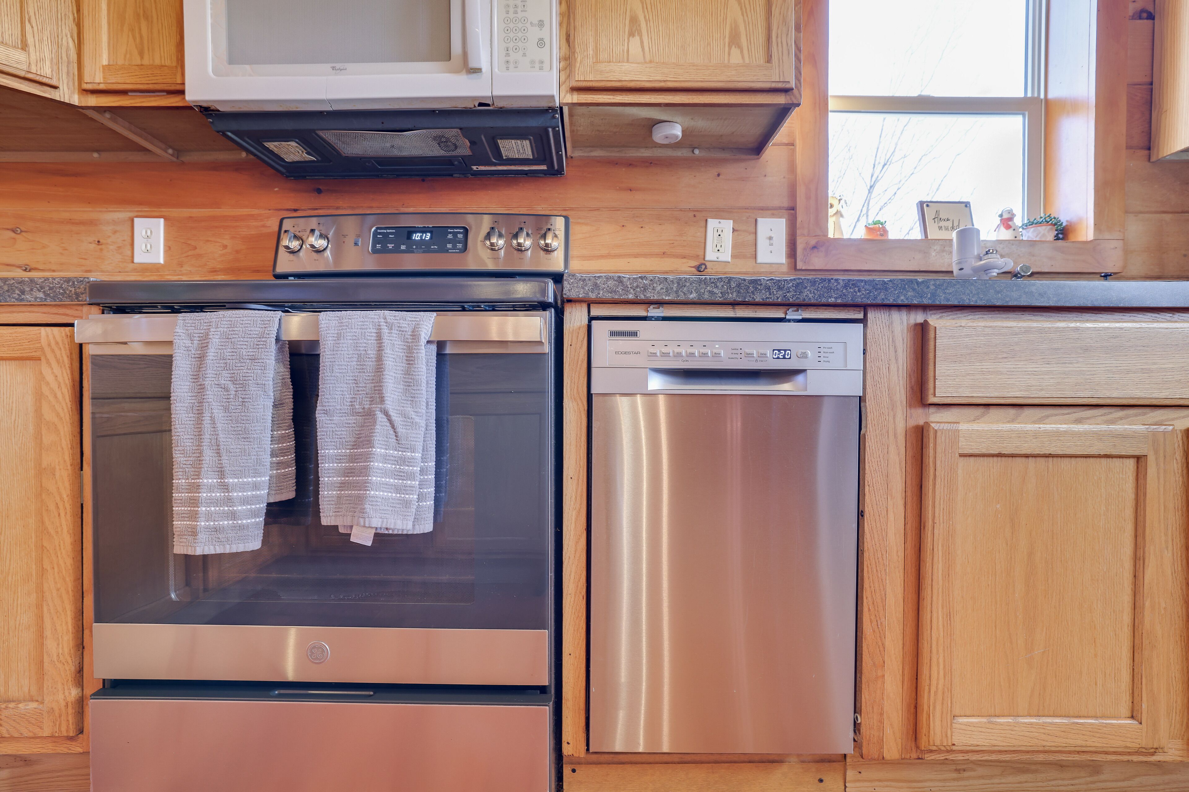 A kitchen with wooden cabinets, a stainless steel oven, a dishwasher, and a microwave.