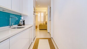 Et moderne køkken med hvide skabe, en blå backsplash og en kaffemaskine.