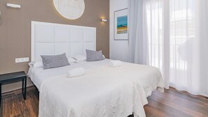 Una camera d'albergo con un letto grande, un elemento decorativo a parete rotondo, un quadro e una finestra con tende.