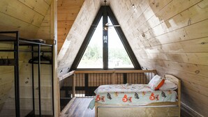 A loft-style bedroom with a sloped ceiling, a bunk bed, and a window providing a view of the outdoors. - Picturesque Mountain Views, Direct Snowmobile & ATV trail access. 30 minutes to Sunday River and Black Mountain of Maine. (Andover)