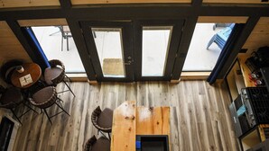 A wooden interior with a kitchen area, a dining table with chairs, and a view through large windows. - Picturesque Mountain Views, Direct Snowmobile & ATV trail access. 30 minutes to Sunday River and Black Mountain of Maine. (Andover)