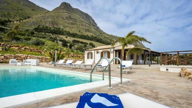 A pool area with lounge chairs and a view of a mountain. - Mari e Monti by Interhome (Castellammare del Golfo)