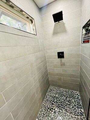 Une douche aux carreaux gris et au sol décoré de motifs de galets.