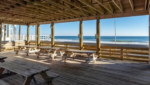 Een houten terras met picknicktafels met uitzicht op de oceaan.